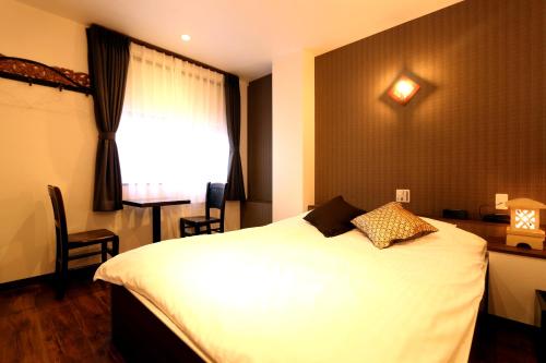 a bedroom with a white bed and a window at Hotel 3 O'Clock Tennoji in Osaka