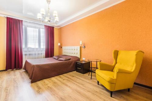 ブズルクにあるApartments on Moskovskaya 79のベッドルーム1室(ベッド1台、黄色い椅子付)