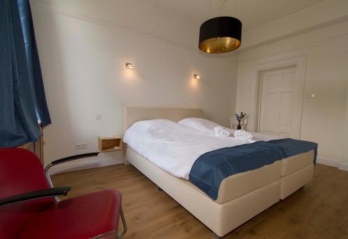 a bedroom with a bed and a red chair at B&B Villa Anna, Venlo in Venlo