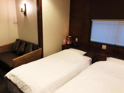 a bedroom with two beds and a chair and a window at Hotel 3 O'Clock Tennoji in Osaka