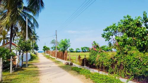 a dirt road next to a field with trees at Sampalthivu Beach Villa in Trincomalee