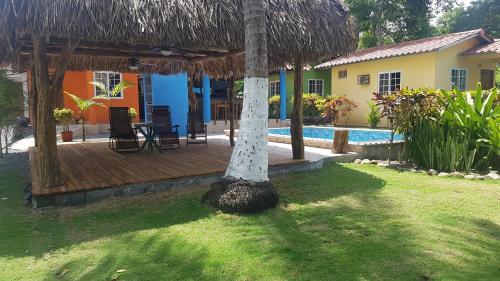 une maison dotée d'une terrasse en bois avec un palmier dans l'établissement Sunrise Inn, à Puerto Armuelles