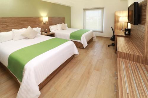 a hotel room with two beds and a flat screen tv at Wyndham Garden Monterrey Valle Real in Monterrey