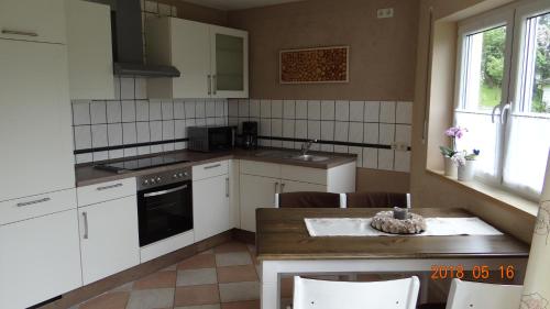 a kitchen with white appliances and a table and chairs at Ferienwohnung Weitermann in Berg