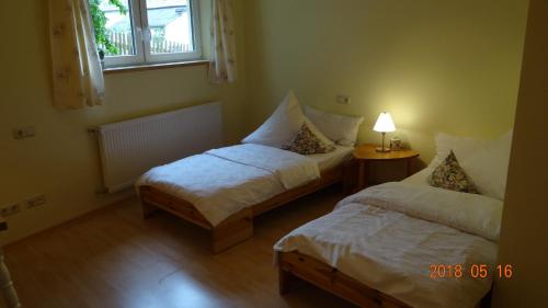 a room with two beds and a lamp and a window at Ferienwohnung Weitermann in Berg