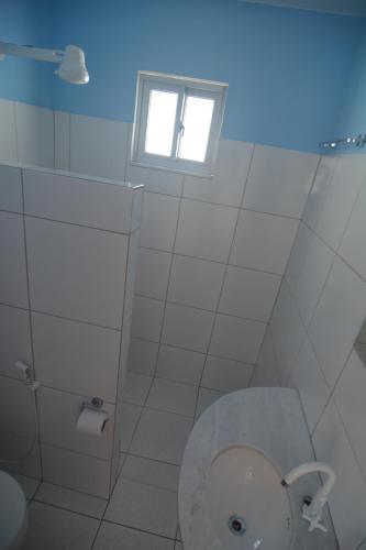 a white bathroom with a toilet and a window at Brasil-Kite in Paracuru