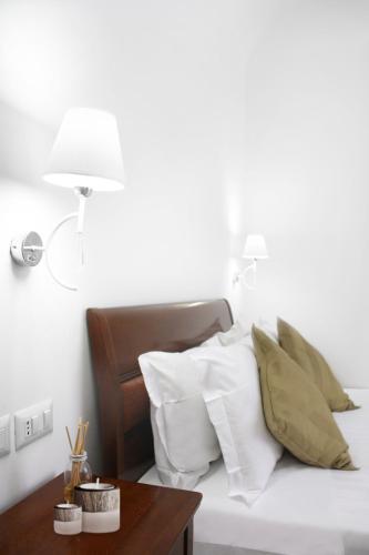 a bed with white pillows and a table with a lamp at Roma Resort Colosseum in Rome