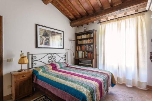 a bedroom with a bed and a book shelf and a window at Casale Lombriciano in Cortona