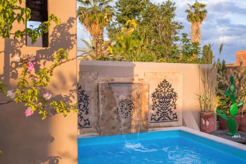 a swimming pool with a fountain in a garden at Riad Swaka in Marrakesh