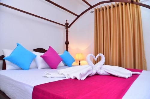 1 dormitorio con 1 cama con toalla en forma de corazón en Sunshine Greens, en Hikkaduwa
