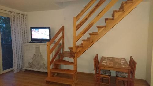 a living room with a staircase with a table and a television at Apartament w centrum "Jagoda"przy Placu Neptuna in Międzyzdroje