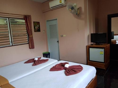 two beds in a room with red robes at Noble Night Guesthouse in Kanchanaburi