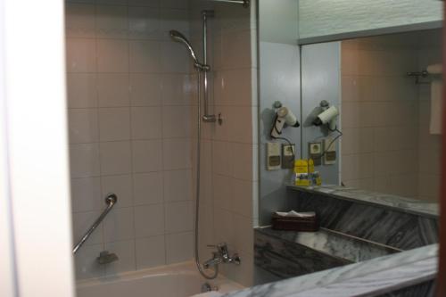 a bathroom with a shower and a tub and a mirror at CITIC Hotel Beijing Airport in Shunyi