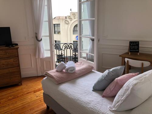 Un dormitorio con una cama con almohadas rosas y una ventana en BAires Boutique Rooms en Buenos Aires