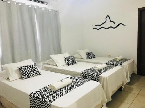 a room with three beds and a wave on the wall at Pousada Morro do Pico in Fernando de Noronha
