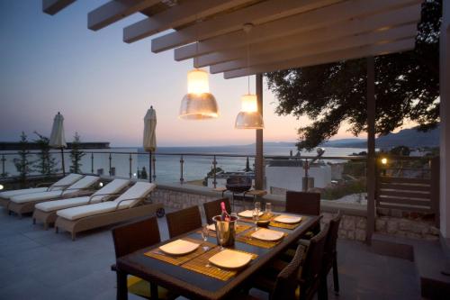 un patio con tavolo, sedie e vista sull'oceano di Blue Dream Luxury Villas a Pefki Rhodes