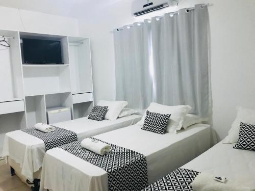 a room with two beds and a flat screen tv at Pousada Morro do Pico in Fernando de Noronha