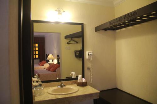 a bathroom with a sink and a mirror and a bed at Hotel Zaci in Valladolid