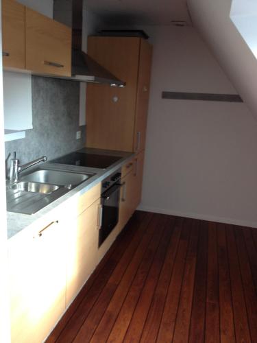 a kitchen with a sink and a wooden floor at gîtes au domaine Greiner in Mittelwihr