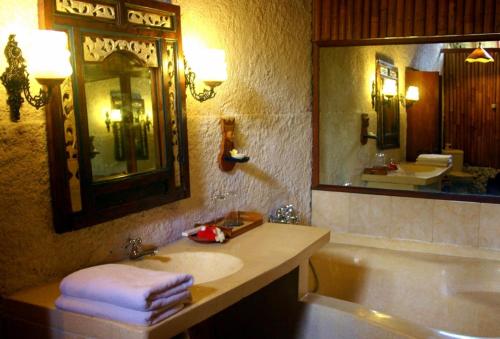 een badkamer met een wastafel, een bad en een spiegel bij Puri Cendana Resort Bali in Seminyak