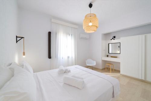 a white bedroom with a large white bed with two towels at En Lefko in Sitia