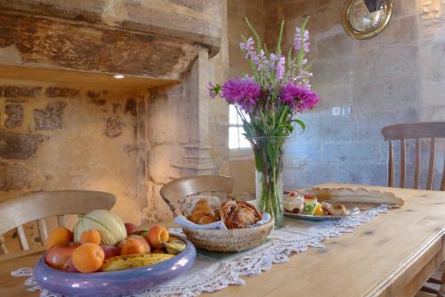 a table with bowls of fruit and a vase of flowers at Rue Bertrand de Got in Saint-Cyprien