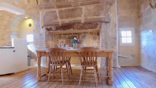 een keuken met een houten tafel met stoelen en een open haard bij Rue Bertrand de Got in Saint-Cyprien