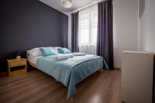 ゴジュフ・ヴィエルコポルスキにあるFUDA APARTAMENT BRUKSELSKA 11のベッドルーム1室(青いシーツと窓付)