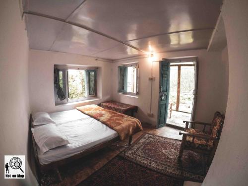a small bedroom with a bed and a window at NotOnMap - Adobe The Cloud in Chitkul