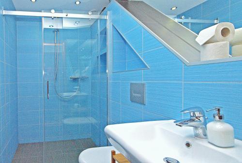 a blue bathroom with a shower and a sink at IRS ROYAL APARTMENTS Apartamenty IRS Morenowe Wzgórza in Gdańsk