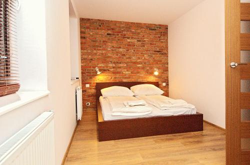 a bed in a room with a brick wall at IRS ROYAL APARTMENTS Apartamenty IRS Morenowe Wzgórza in Gdańsk