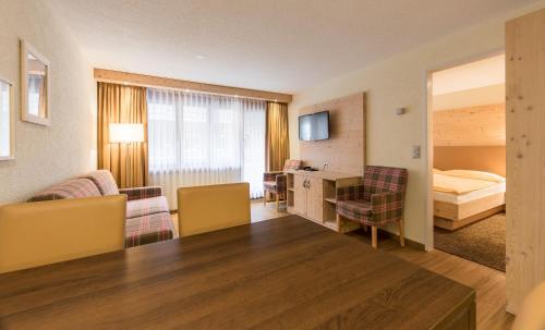 a hotel room with a bed and a living room at Hotel Derby in Zermatt