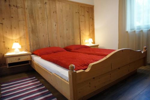 a bedroom with a large wooden bed with red sheets at Klösterle 2018 in Lutago