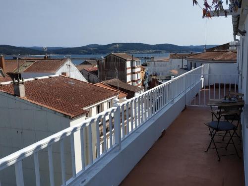 a balcony with a white railing and a table and chairs at A CARAMIÑA in Camariñas