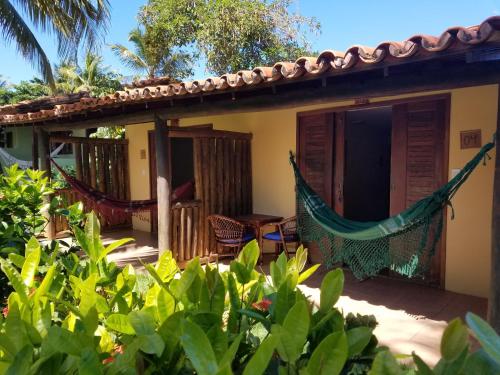 a house with a hammock on the porch at Pousada Praia das Ondas - Pé na areia in Itacimirim
