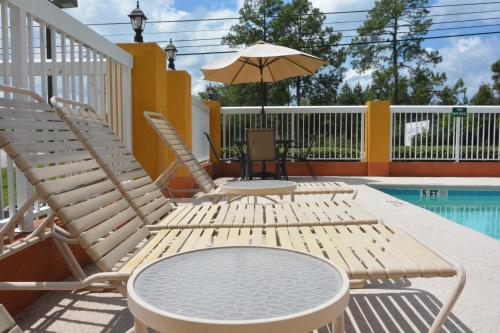 a patio with two chairs and an umbrella next to a pool at Jameson Inn and Suites Hazelhurst in Hazlehurst