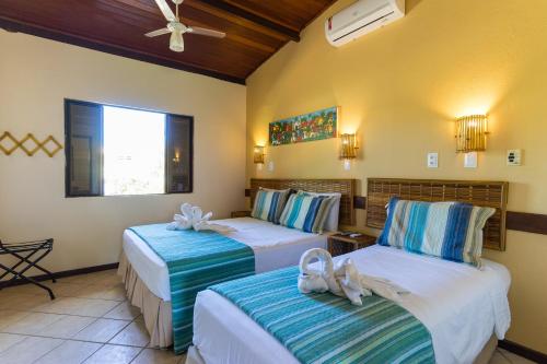 a hotel room with two beds with towels on them at Pousada Praia das Ondas - Pé na areia in Itacimirim