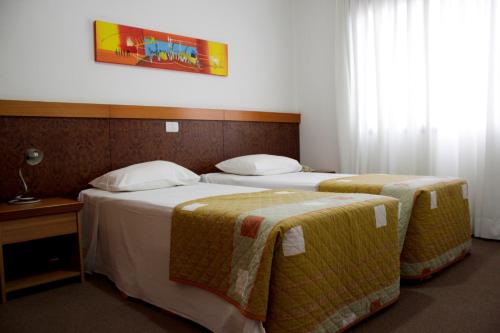 a hotel room with two beds and two lamps at Apto no Union Residence in Novo Hamburgo