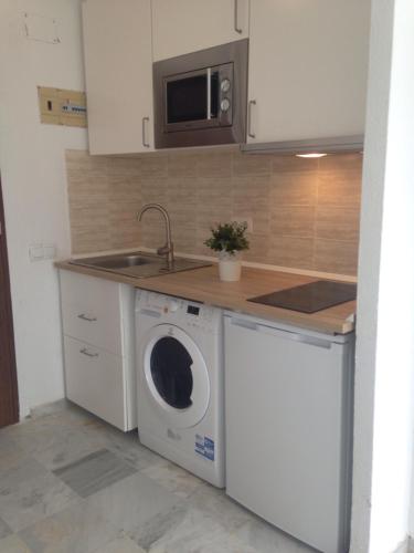 a kitchen with a washing machine and a microwave at Apartamentos vista a tres continentes in La Línea de la Concepción