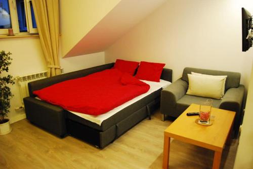 łóżko z czerwonymi poduszkami i kanapą w pokoju w obiekcie Bed & Breakfast Sielce Warszawa Chełmska w Warszawie