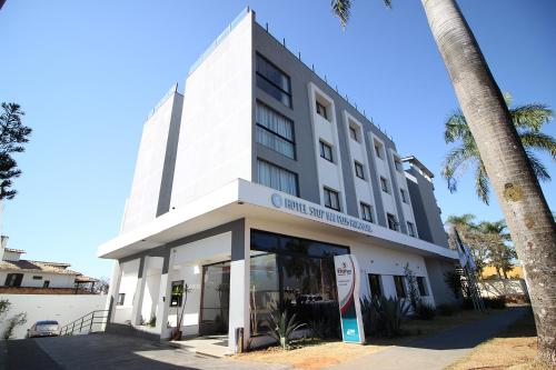 un edificio blanco con una palmera delante en Stop Inn Plus Pampulha, en Belo Horizonte