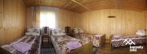 una camera con tre letti in una camera in legno di Котедж Ялівець a Kolochava