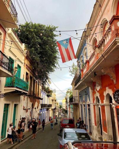 a group of people walking down a street with a flag at Navona Studios in San Juan