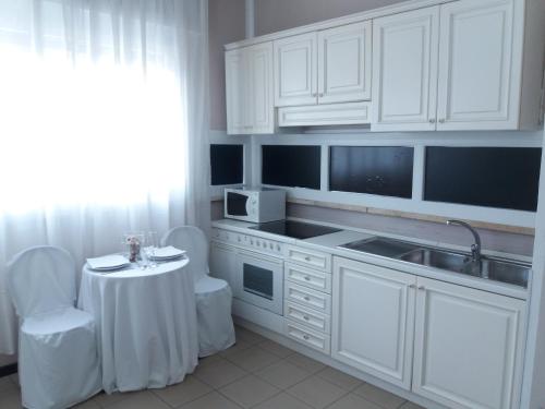 a kitchen with white cabinets and a table and a sink at San Donato Apartment in Turin