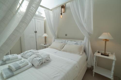 a white bedroom with a white bed with towels on it at Poseidon Mansion Sunset in Oia