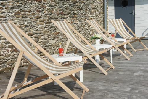 a row of lawn chairs sitting on a porch at Gîtes Le Bout du Monde in Le Conquet