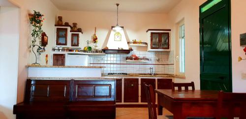 una cucina con armadi in legno, tavolo e luce di corrente di Villa Leo a Terracina