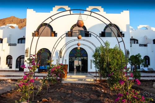 a white building with an archway and flowers at Daniela Diving Resort Dahab in Dahab