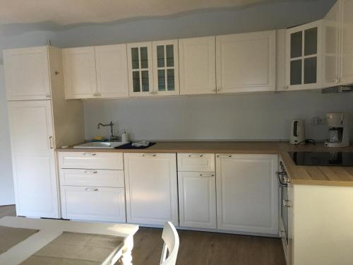 a white kitchen with white cabinets and wooden floors at Ferienscheune Juhlsgaard in Husby
