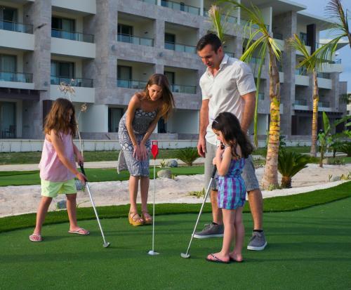 a man and two girls playing a game of golf at Royalton Bavaro, An Autograph Collection All-Inclusive Resort & Casino in Punta Cana